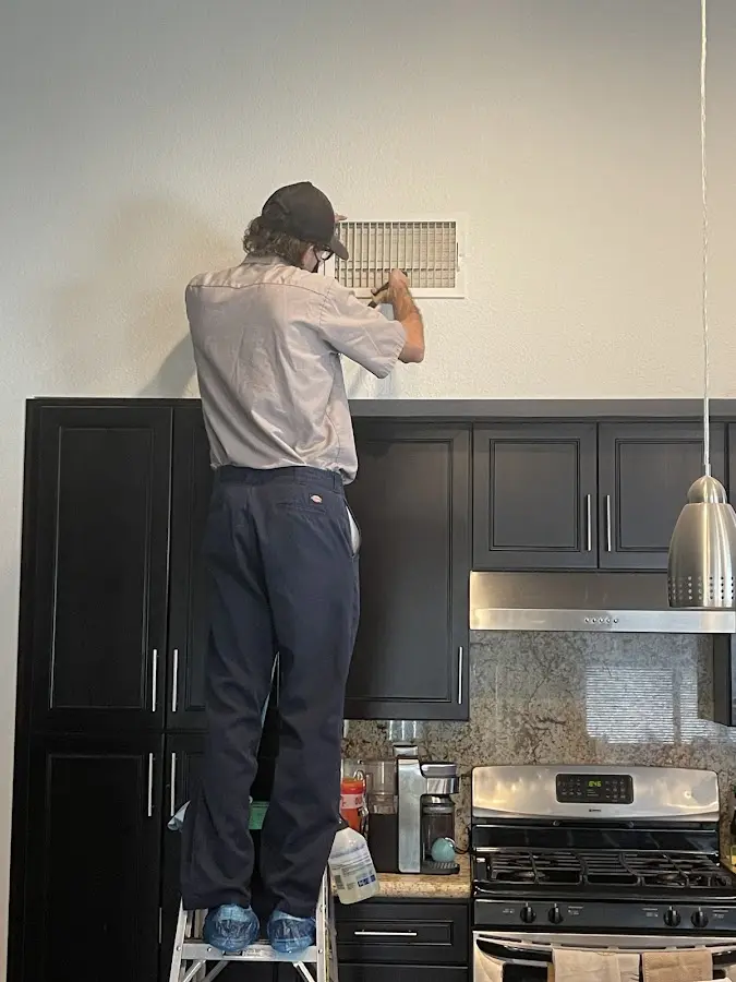 Technician inspecting an air vent during HVAC service in West Miami